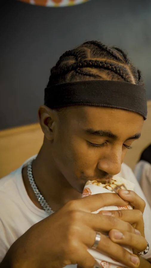 Un client croque dans son tacos au restaurant O’Tacos